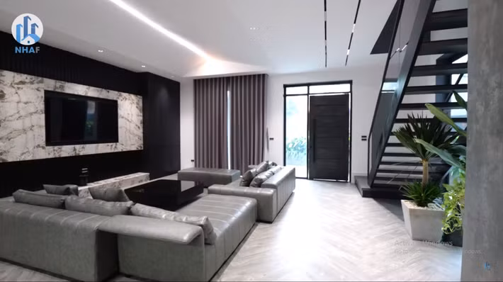 Ngôi nhà phố gồm có 2 tầng. Phòng khách ở tầng 1 thiết kế theo phong cách hiện đại với gam màu tối chủ đạo.