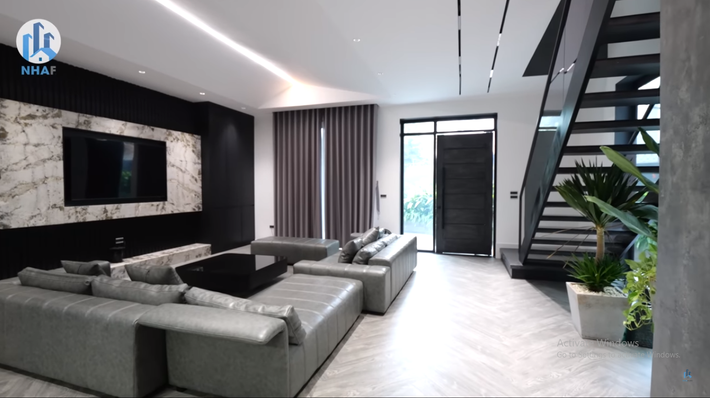 Ngôi nhà phố gồm có 2 tầng. Phòng khách ở tầng 1 thiết kế theo phong cách hiện đại với gam màu tối chủ đạo.