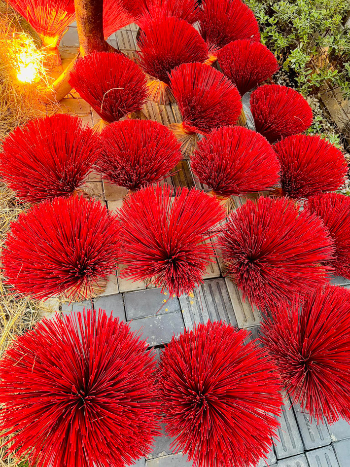Những bó hương tre đỏ sắp xếp gọn gàng, tạo hình bắt mắt dưới tán cây mai giả. Ảnh: FB Đoàn Di Băng