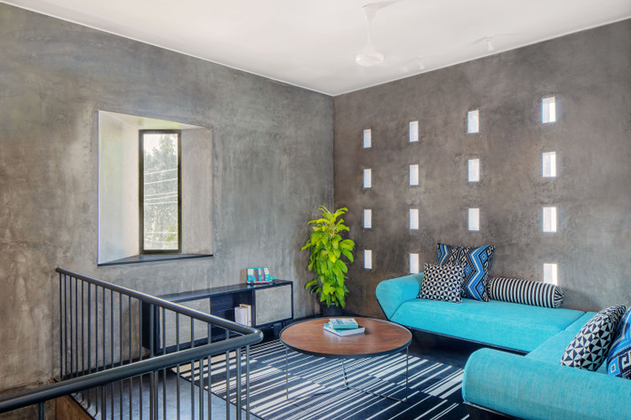 Phòng khách lạ mắt với sự đối lập giữa bức tường màu xám và sofa màu xanh.