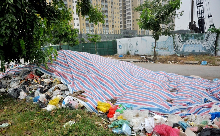 Ban quản lý tòa nhà dùng tấm bạt lớn nhưng chỉ phủ được một phần đống rác thải. Ảnh: Batdongsanvietnam.