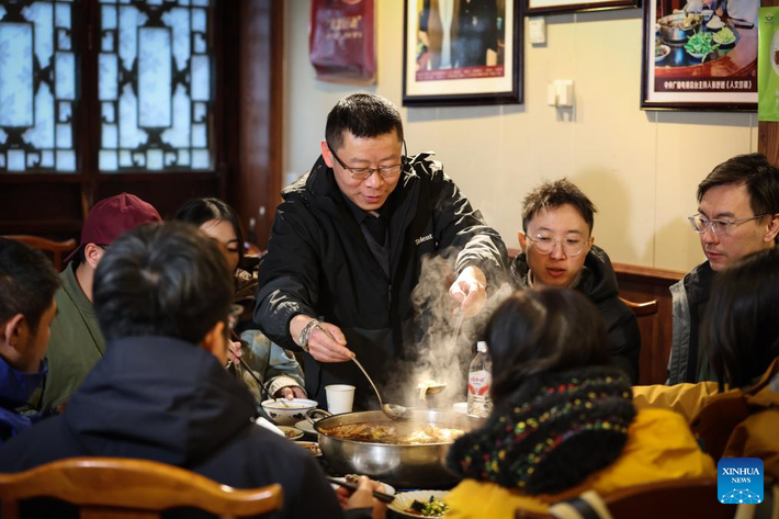 Ông Zhai Zhigang, chủ một nhà hàng, đang phục vụ khách tại nhà hàng của mình trong thị trấn ngày 13/12/2025.