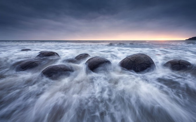 Những khối đá Moeraki nổi tiếng lúc bình minh. Những khối đá hình cầu khổng lồ này, được hình thành từ đá trầm tích cổ đại cách đây hàng chục triệu năm, nằm trên bãi biển Koekohe thuộc bờ biển Otago.