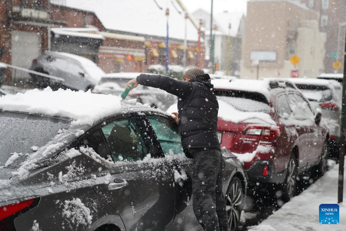 Người đàn ông dọn tuyết trên chiếc ô tô của anh tại một con phố ở New York ngày 14/12. Ảnh: Xinhua News.
