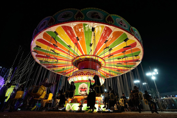 Mọi người thích thú chơi đu quay tại triển lãm công nghiệp ở Hyderabad ngày 28/1.