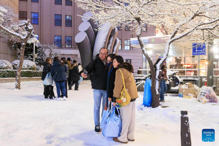 Mọi người chụp ảnh lưu niệm trong trận tuyết rơi đầu mùa ở Seoul ngày 4/12. Ảnh: Xinhua News.