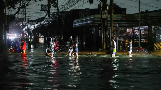 Cơn bão cũng gây ra tình trạng mất điện trên diện rộng, ảnh hưởng đến gần 3 triệu hộ gia đình trên khắp Philippines hôm 9/11. Ảnh: Người dân mang theo đồ đạc lội qua con phố ngập nước giữa lúc mất điện tại Metro Manila, Philippines, ngày 10/11/2025. Ảnh: AA.