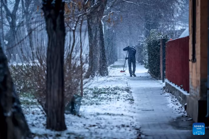 Một người dân đang dọn tuyết trên đường phố Budapest trong một ngày mùa đông lạnh giá. Ảnh: Xinhua.