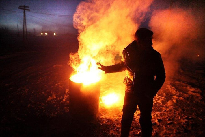 Người đàn ông sưởi ấm bên đống lửa trong ngày đông lạnh giá. Ảnh: Smithsonian.