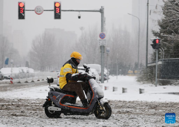 Người giao hàng di chuyển dưới trời tuyết rơi.