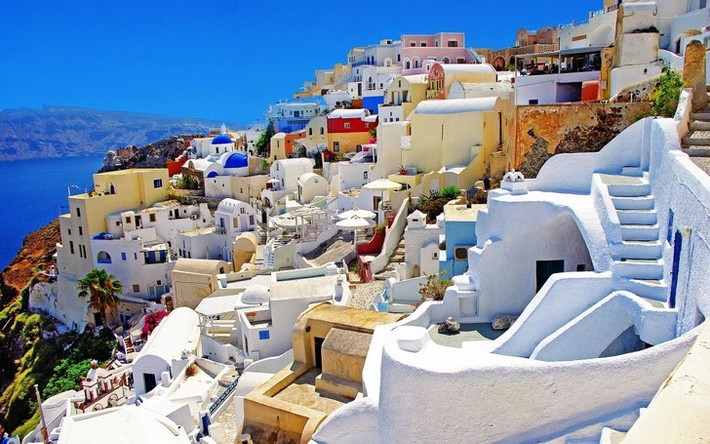 Vùng đất Santorini ở Hy Lạp có những ngôi nhà sơn trắng nằm trải dài trên vách đá, với điểm nhấn là cửa và mái nhà màu xanh dương cùng tầm nhìn hướng ra biển.