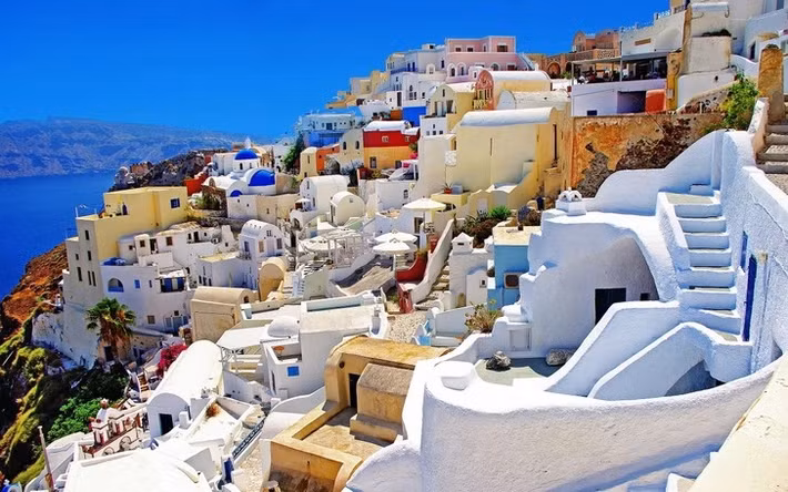 Vùng đất Santorini ở Hy Lạp có những ngôi nhà sơn trắng nằm trải dài trên vách đá, với điểm nhấn là cửa và mái nhà màu xanh dương cùng tầm nhìn hướng ra biển.