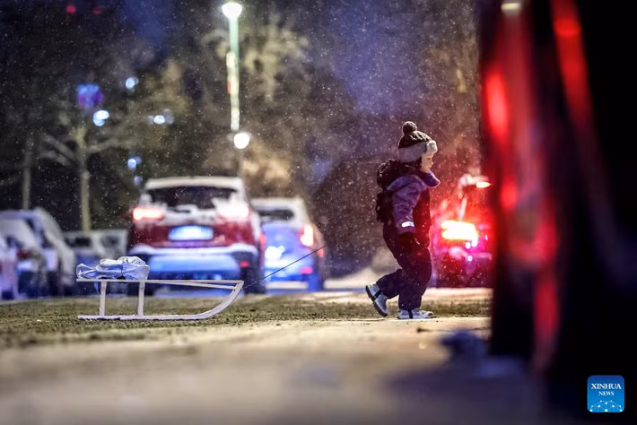 Một em nhỏ đi dưới trời tuyết rơi ở thủ đô Budapest. Ảnh: Xinhua.