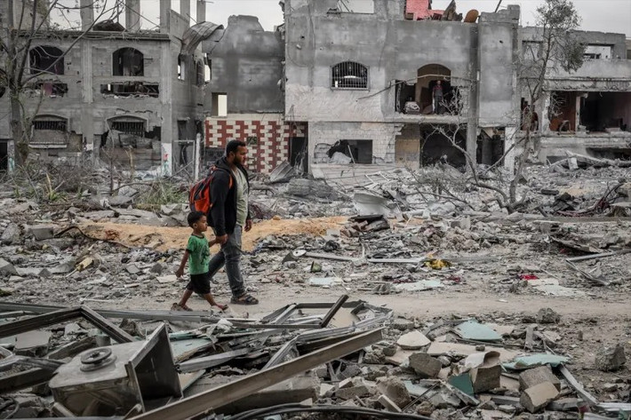 Người cha dẫn con nhỏ đi qua những ngôi nhà bị phá hủy ở khu phố Sabra, thành phố Gaza, hôm 12/10. Được biết, hầu hết tòa nhà ở thành phố Gaza đều không còn nguyên vẹn sau các cuộc tấn công trước đó của Israel. Ảnh: Anadolu.