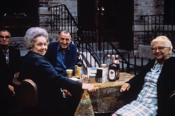 Một nhóm người lớn tuổi ngồi uống nước, trò chuyện trên vỉa hè ở Brooklyn. Ảnh: Facebook.