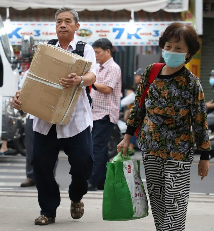 Tại cổng ga Dĩ An, dòng người xuống xe khách, mang theo vali, túi xách, tiếp tục hành trình trên đường sắt.