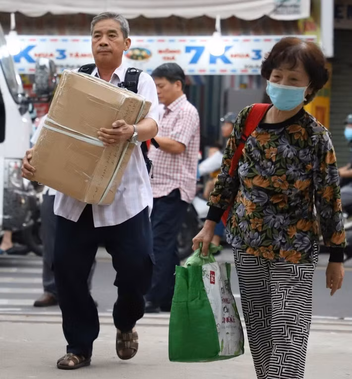 Tại cổng ga Dĩ An, dòng người xuống xe khách, mang theo vali, túi xách, tiếp tục hành trình trên đường sắt.