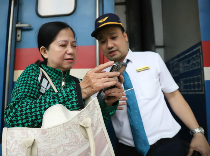 Nữ hành khách hỏi nhân viên ngành đường sắt vị trí toa tàu để thuận lợi di chuyển.