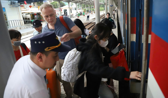 Nhân viên đường sắt hướng dẫn các toa xe cho hành khách lên tàu tại ga Dĩ An