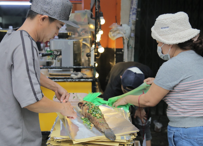 Cá sau khi được nướng lại quét thêm lớp mỡ hành và gói trong giấy bạc để khách mang về..