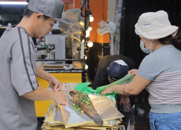 Cá sau khi được nướng lại quét thêm lớp mỡ hành và gói trong giấy bạc để khách mang về..