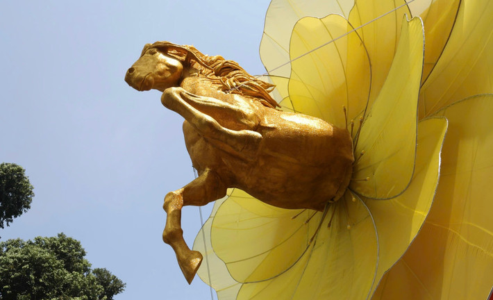 Du khách bị thu hút bởi hình ảnh một chú ngựa vàng dũng mãnh đang phi nước đại, vươn mình ra từ tâm của một đóa hoa mai khổng lồ rực rỡ.