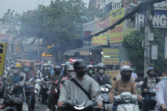 Khói từ các bếp than nướng cá lóc bay mù mịt ra đường khiến việc lưu thông của người dân gặp khó khăn do bị cay mắt.