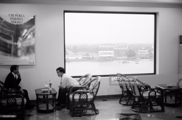 Hai người đàn ông trò chuyện trong một quán cà phê "view" sông Sài Gòn.