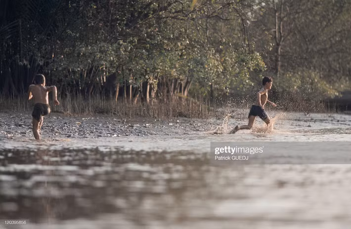 Các cậu bé chơi đùa trên bờ sông ở đồng bằng sông Cửu Long.