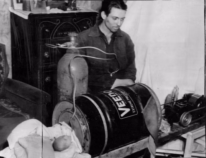 James Bailey, 25 tuổi, nhìn con trai mới sinh của mình nằm trong "Phổi thép" anh tự chế bằng thùng dầu, lốp xe và động cơ máy giặt, 15/3/1940. Cậu bé chỉ sống được hai ngày.