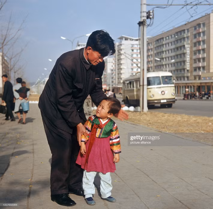 Hai cha con trên phố Chollima. Người cha mặc trang phục công sở điển hình, còn bé gái mặc bộ hanbok - trang phục truyền thống Triều Tiên - dành cho trẻ em.