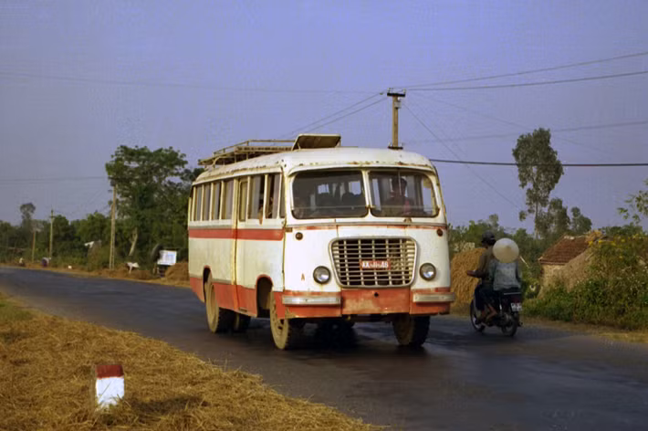 Một chiếc xe buýt quân đội mang biển số AA-11-48 chạy trên con đường ngoại ô Hà Nội.
