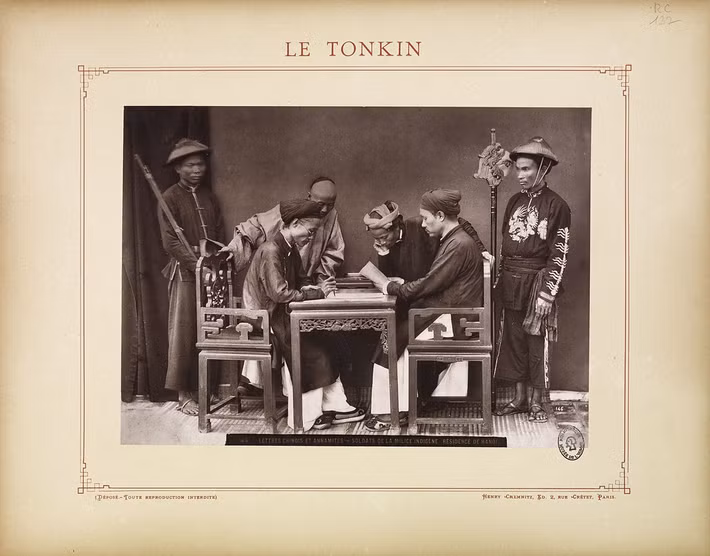 Hai ông quan xem xét các văn thư, xung quanh là vài thường dân và binh lính.