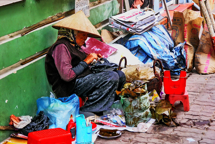 Cụ bà bán bánh giò trên vỉa hè.