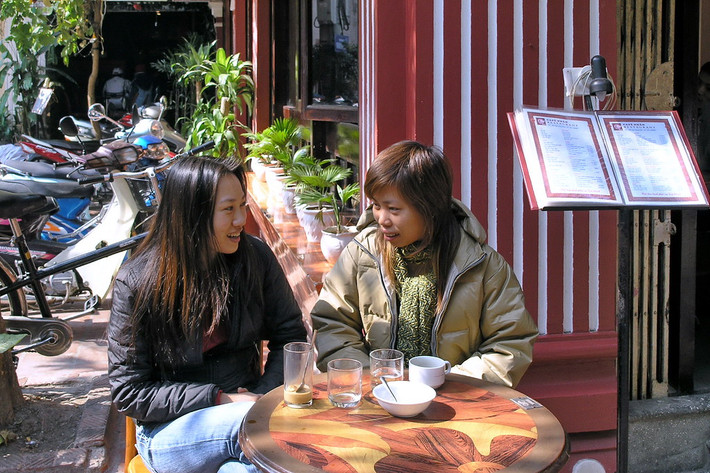 Hai người đẹp thưởng thức cà phê bên vỉa hè.