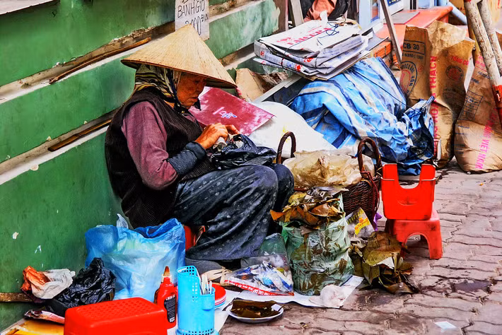 Cụ bà bán bánh giò trên vỉa hè.