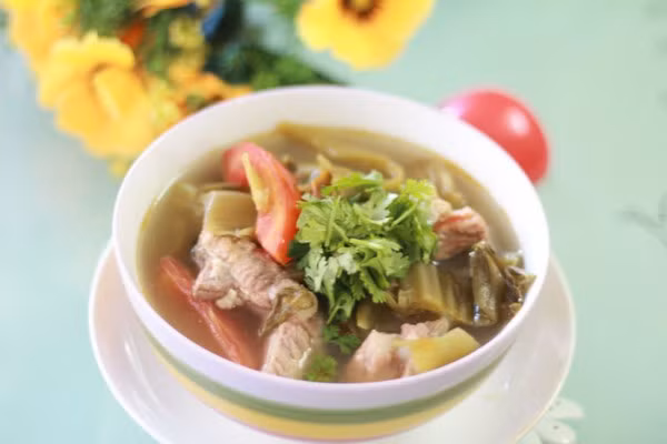 Sườn nấu dưa chua: Sườn rửa sạch, cắt khúc, luộc sơ qua một lần nước rồi để ráo. Sau đó cho sườn vào tô, ướp với hạt nêm, muối cho ngấm gia vị khoảng 30 phút. Cho sườn vào nồi đảo sơ rồi để ra bát riêng.