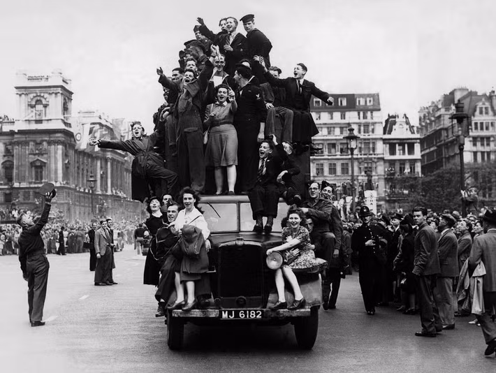 Nhiều người trèo trên một chiếc xe tải quân sự trên đường phố London để ăn mừng thời khắc quân đồng minh đánh bại phát xít Đức và Thế chiến 2 đi đến hồi kết.
