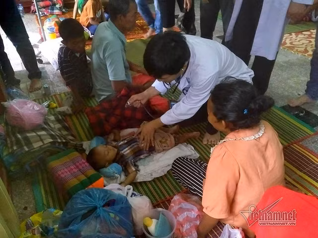 Bác sĩ nghe khám phổi cho em bé 9 tháng tuổi vừa thoát khỏi lũ dữ