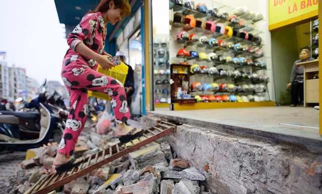 Người dân ở phố Xã Đàn (quận Đống Đa) bắc thang vào nhà sau khi bậc tam cấp bị phá dỡ. Ảnh: Lê Hiếu.