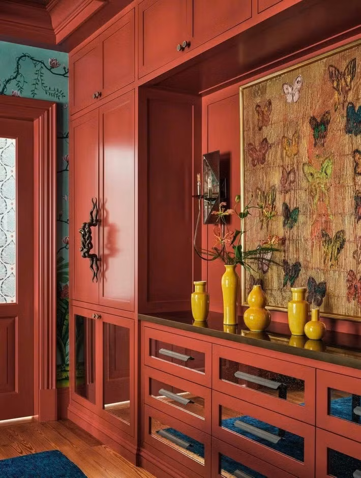 Tủ đựng đồ ăn tích hợp trong phòng ăn, được sơn màu Flamenco của hãng Benjamin Moore, kết hợp giữa không gian lưu trữ kín đáo với các hốc trưng bày mở dành cho tranh ảnh và đồ vật sưu tầm.