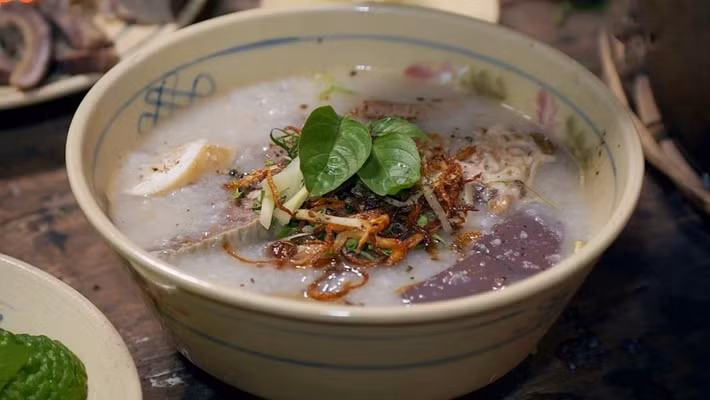 Nếu muốn khám phá thêm nét riêng trong ẩm thực vùng Bảy Núi, cháo bò Tri Tôn là món ăn không nên bỏ lỡ. Cháo có độ dẻo thơm, nước dùng ngọt từ xương bò, kết hợp với thịt bò, lòng bò và huyết. Điểm nhấn đặc biệt nằm ở vị chua thanh nhẹ của trái chúc, hòa cùng gừng thái sợi, hành lá và ớt, tạo nên hương vị đậm đà đặc trưng. Ảnh: ivivu