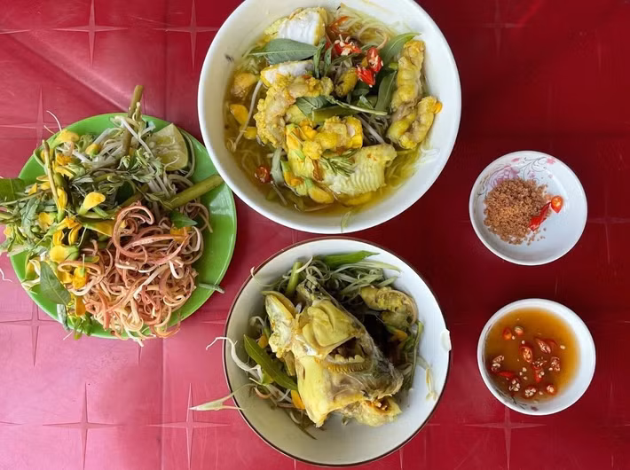 Nhắc đến ẩm thực An Giang, bún cá Long Xuyên là món ăn được nhiều du khách yêu thích. Món ăn gây ấn tượng với nước dùng vàng óng từ nghệ tươi, có vị thanh ngọt của cá lóc đồng. Thịt cá mềm thơm, ăn cùng bún, bắp chuối bào, rau nhút và bông điên điển, tạo nên sự hài hòa giữa vị đậm đà và thanh mát. Ảnh: Vinwonders