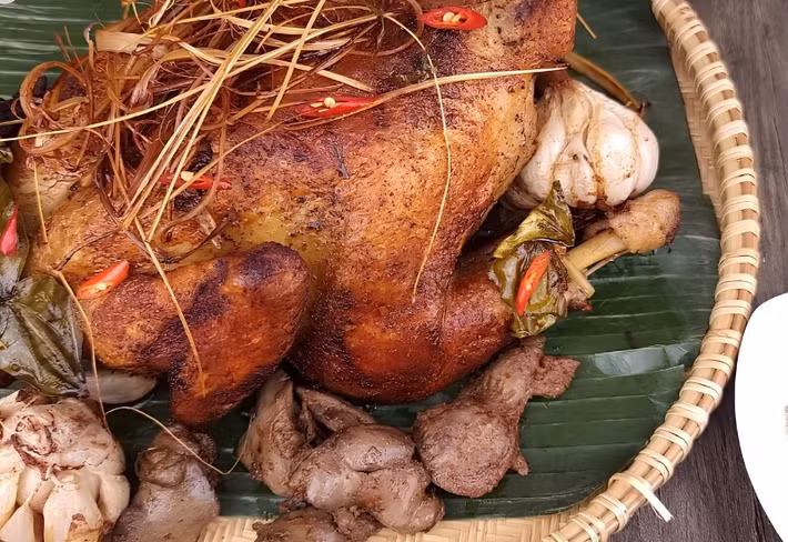 Không chỉ có các món nước, An Giang còn nổi tiếng với gà đốt lá chúc Ô Thum. Gà được tẩm ướp sả, ớt, tỏi rồi đốt trong nồi đất cùng lá chúc, giúp thịt giữ được độ mềm ngọt và lớp da vàng óng hấp dẫn. Hương thơm đặc trưng của lá chúc khiến món ăn trở nên khác biệt, nhất là khi dùng cùng xôi đậu xanh, rau rừng và muối tiêu chanh. Ảnh: Arttimes