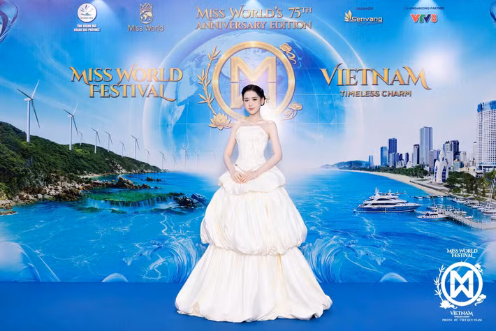 Á hậu Trương Tâm Như diện váy quây màu trắng kem với phần thân corset và chân váy xếp tầng tạo độ phồng. Thiết kế mang phom công chúa, khác với loạt váy ôm dáng xuất hiện trên thảm đỏ.