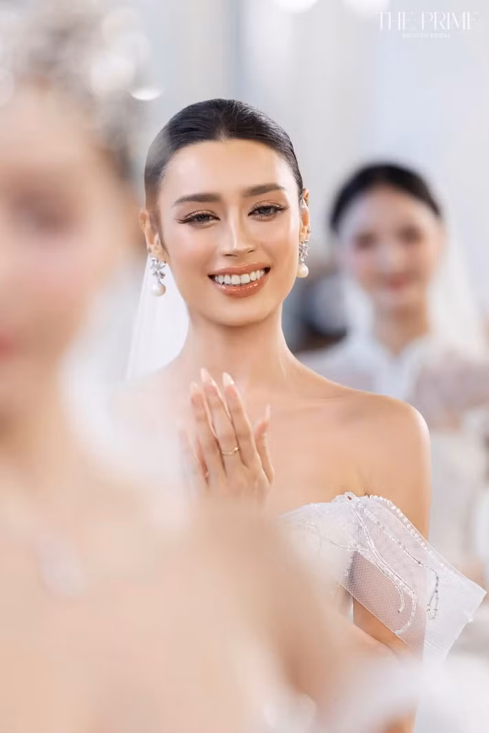 Khi làm người mẫu trình diễn váy cưới, Emoura Phạm chuyển sang hình ảnh nhẹ nhàng, nữ tính. Nụ cười tươi cùng cách trang điểm tự nhiên mang đến cho cô vẻ mềm mại hơn.