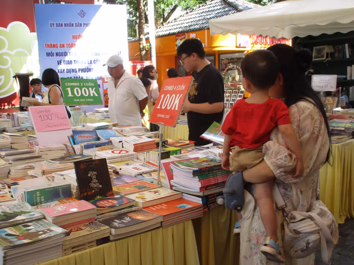 Nhiều em nhỏ cùng cha mẹ hào hứng dừng chân rất lâu tại các gian hàng sách thiếu nhi để tự tay tìm kiếm, đọc thử và chọn lựa những cuốn sách. (Ảnh: Bảo Châu)