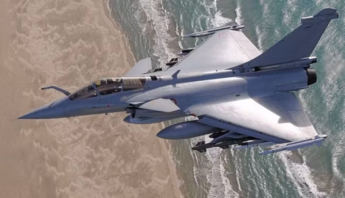 Tiêm kích Dassault Rafale của Pháp bay thấp dọc theo bờ biển, mang theo thùng nhiên liệu phụ và tên lửa dưới cánh trong một nhiệm vụ huấn luyện ﻿hoặc tuần tra trên không.