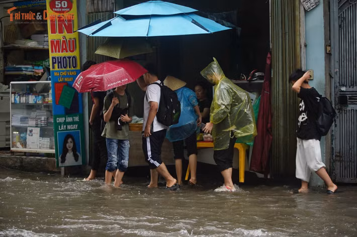 Với nhiều người, việc đến cơ quan trong buổi sáng mưa ngập trở thành hành trình không dễ dàng. Những đoạn đường nước sâu khiến người đi xe máy phải giảm tốc độ, thậm chí xuống xe dắt bộ để tránh phương tiện chết máy hoặc mất thăng bằng.