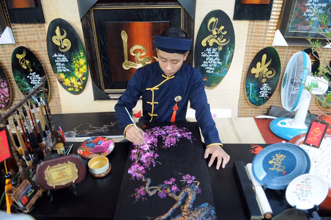Và cả vẽ tranh hoa đào bán cho khách tham quan. 